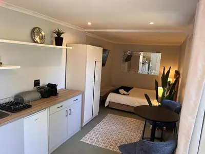 a small kitchen with a bed and a table in a room at Secluded Silver Mile with solar back-up in Cape Town