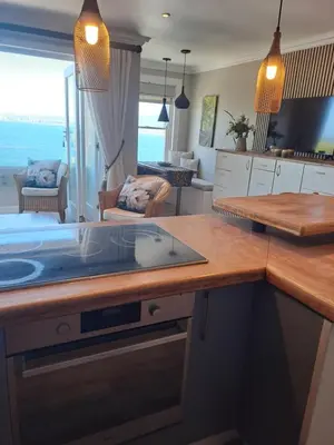 a kitchen with a counter top and a living room at Boutique Inn - Whale Pod in Gordonʼs Bay