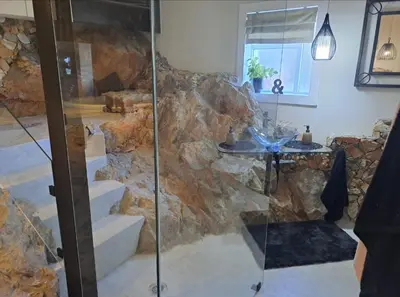 a bathroom with a glass shower and a stone wall at Boutique Inn - Whale Pod in Gordonʼs Bay