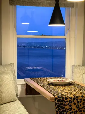 a table in a room with a view of the ocean at Boutique Inn - Whale Pod in Gordonʼs Bay