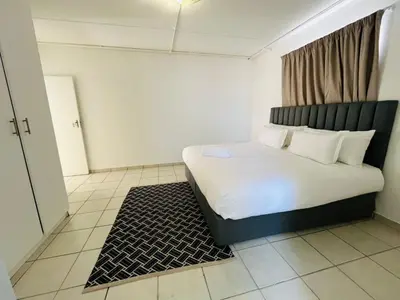 a bedroom with a bed with white sheets and pillows at Eversham Boutique in Cape Town