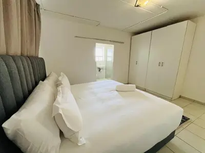 a bedroom with a white bed with white pillows at Eversham Boutique in Cape Town