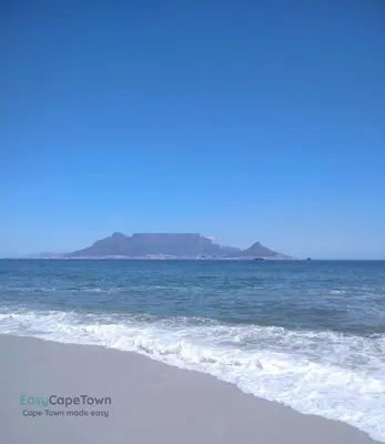 a view of the beach with a mountain in the background at EasyCapeTown - Bloubergstrand coastal apartment in Cape Town
