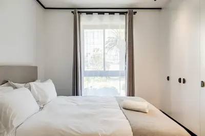 a bedroom with a white bed with a window at Palmcrest Eden in Cape Town