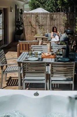 a woman sitting at a table on a patio at Onrus Sunshine Beach Days in Hermanus