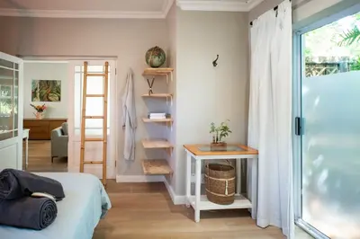 a bedroom with a bed and a table and a window at Onrus Sunshine Beach Days in Hermanus