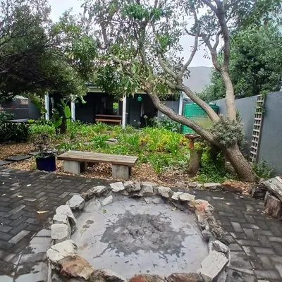 a stone patio with a bench and a tree at Awesome cottage, stone throw from cliff path, golf, restaurant in Hermanus