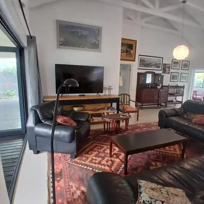 a living room with a couch and a table at Awesome cottage, stone throw from cliff path, golf, restaurant in Hermanus