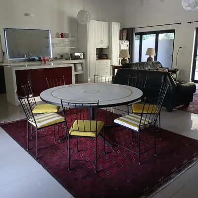 a table and chairs in a living room with a kitchen at Awesome cottage, stone throw from cliff path, golf, restaurant in Hermanus