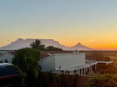 a sunset over a house with mountains in the background at Egret's Lookout in Cape Town