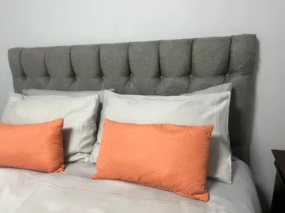 a bed with an orange pillow and white pillows at Oryx guest house in Oakdale