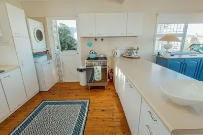 a kitchen with white cabinets and a sink and a counter at Seabreeze in Hermanus