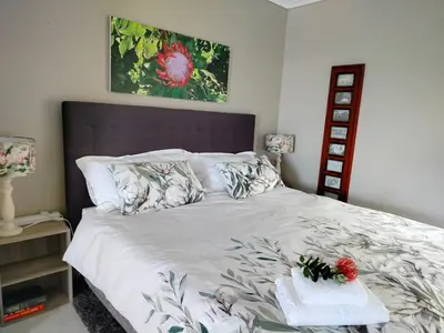 a bedroom with a large bed with flowers on it at Take A Break in Bettyʼs Bay