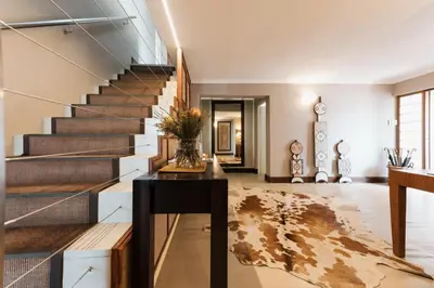 a living room with a staircase with a vase of flowers at Whale Away Guest House in Hermanus