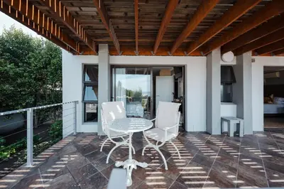 a patio with a table and white chairs at Whale Away Guest House in Hermanus