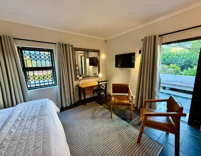 a hotel room with a bed and a desk and a window at 1 at Huis Piron in Stellenbosch