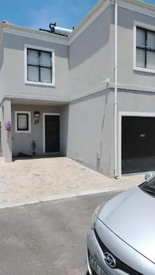 a white house with a car parked in front of it at Tin Home 88 in Cape Town