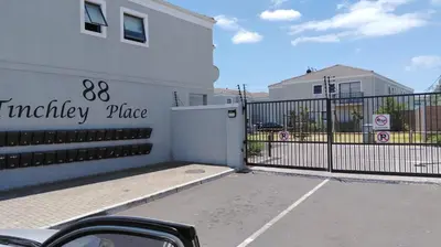 a white building with a gate in a parking lot at Tin Home 88 in Cape Town