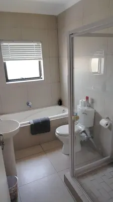 a bathroom with a tub and a toilet and a sink at Tin Home 88 in Cape Town