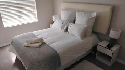 a bedroom with a bed with white sheets and pillows at Tin Home 88 in Cape Town