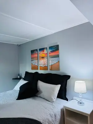 a bedroom with a bed with four paintings on the wall at Worcester Cozy Stay - Apto 2 in Worcester