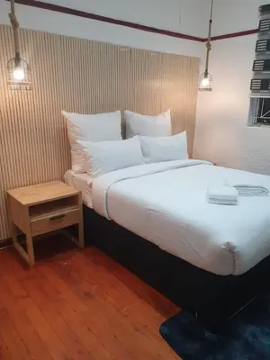 a large bed with white pillows and a night stand at Ludinz Accomodation Self Catering in Avondale