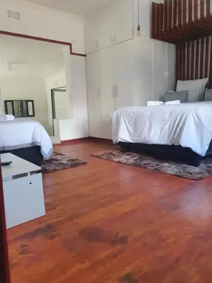 a bedroom with two beds and a wooden floor at Ludinz Accomodation Self Catering in Avondale