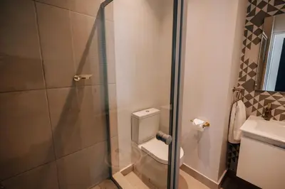 a bathroom with a toilet and a glass shower at 10 at The Alxndr - Stellenbosch Central in Stellenbosch