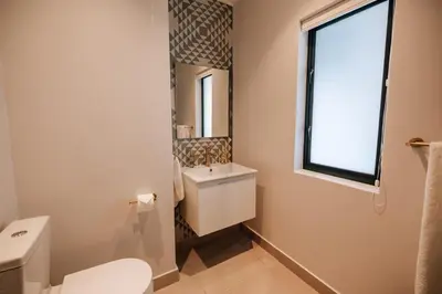 a bathroom with a toilet and a sink and a window at 10 at The Alxndr - Stellenbosch Central in Stellenbosch
