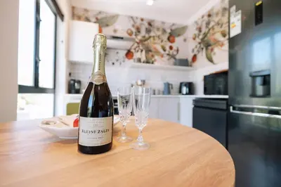 a bottle of wine sitting on a table with two glasses at 10 at The Alxndr - Stellenbosch Central in Stellenbosch