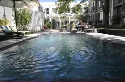 a swimming pool with an umbrella and some chairs at Oude Werf Hotel in Stellenbosch