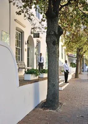 two men standing outside of a building next to a tree at Oude Werf Hotel in Stellenbosch