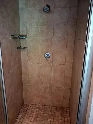 a shower with a glass door and a tiled floor at Pennywhistle in Eersterivier