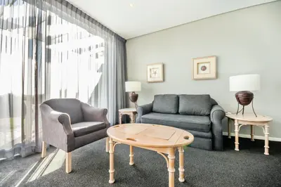a living room with a couch and a chair and a table at Dolphin Beach Hotel Self Catering Apartments in Bloubergstrand