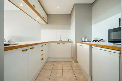 a kitchen with white cabinets and a microwave at Dolphin Beach Hotel Self Catering Apartments in Bloubergstrand