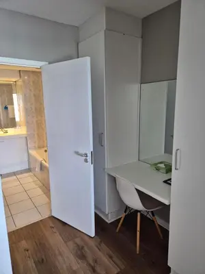 a white room with a desk and a table at Dolphin Beach Hotel Self Catering Apartments in Bloubergstrand
