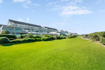 a large green lawn in front of a building at Dolphin Beach Hotel Self Catering Apartments in Bloubergstrand