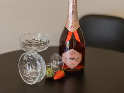 a bottle of wine and a glass with strawberries on a table at Catalyst Guest House in Cape Town