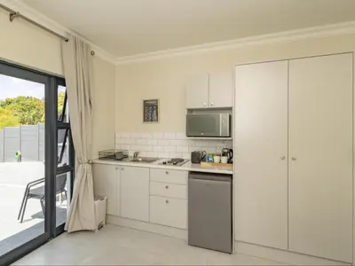 a kitchen with white cabinets and a microwave at Catalyst Guest House in Cape Town