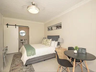 a bedroom with a bed and a table and a desk at Catalyst Guest House in Cape Town