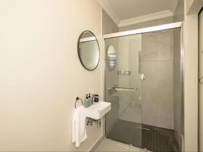 a bathroom with a shower and a sink and a mirror at Catalyst Guest House in Cape Town