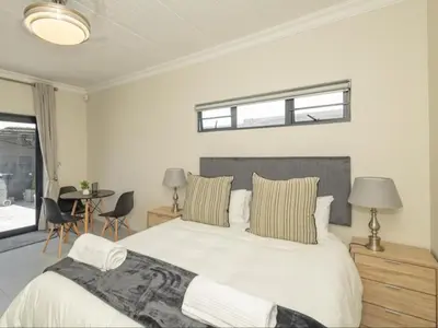 a bedroom with a bed and a table with chairs at Catalyst Guest House in Cape Town