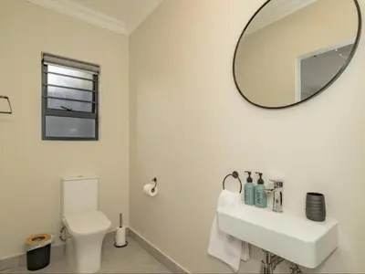 a white bathroom with a sink and a mirror at Catalyst Guest House in Cape Town