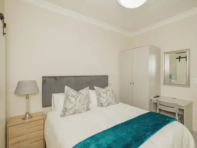 a bedroom with a large white bed and a mirror at Catalyst Guest House in Cape Town