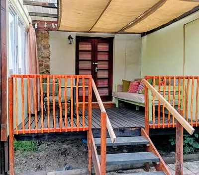 two wooden benches sitting on the porch of a house at Serene, cosy stay with a mountain view in Greyton