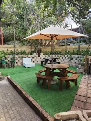 a picnic table with an umbrella on the grass at Log Cabin- Forest, Lagoon Sea location in Hermanus