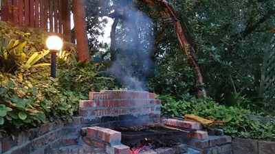 a brick barbecue in a garden with a street light at Log Cabin- Forest, Lagoon Sea location in Hermanus