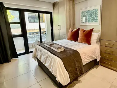a bedroom with a bed and a balcony at 22 at The Den in Stellenbosch