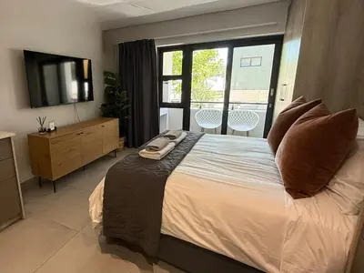 a bedroom with a bed with a television and a balcony at 22 at The Den in Stellenbosch