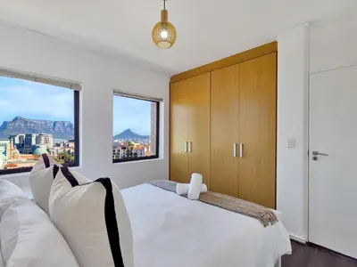a bedroom with a large white bed and a window at Sea, Canal & Mountain View, Rooftop Jacuzzi & BBQ in Cape Town